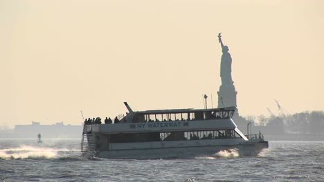 Passenger-Ferries-Pass-Each-Other-In-New-York-Harbor-With-The-Statue-Of-Liberty-In-The-Background