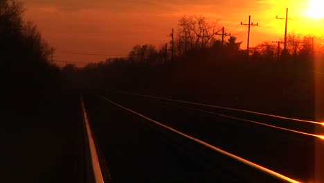 A-Brilliant-Goldenhour-Sky-Casts-Its-Reflection-On-Railroad-Tracks-Stretching-Towards-The-Horizon