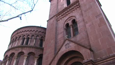 The-Camera-Pans-Up-For-A-Wormseye-View-Of-The-Facade-Of-A-Red-Stone-Church-To-Focus-On-Ornamentation