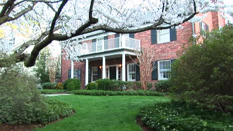 A-Medium-View-Of-Red-Brick-Suburban-Home-In-Early-Spring-With-Flowering-Trees