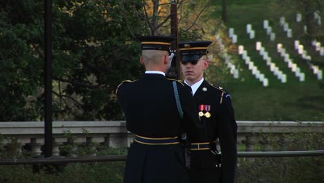 Ein-Soldat-Steht-In-Voller-Uniform-Stramm,-Während-Ein-Anderer-Soldat-Seine-Waffe-Inspiziert