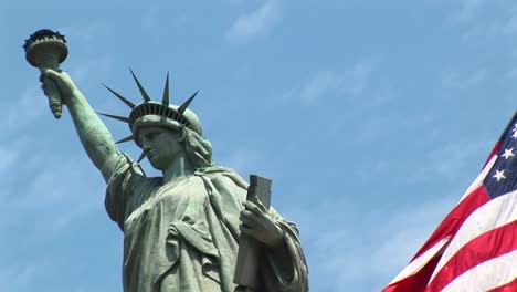 The-Camera-Pansleft-Across-A-Rippling-American-Flag-Revealing-The-Statue-Of-Liberty-In-The-Background