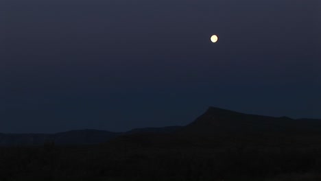 Longshot-Of-The-Moon-Over-A-Rocky-Landscape