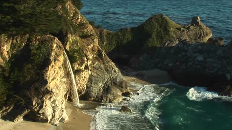Birdseye-Shot-Of-A-Waterfall-Crashing-Down-Into-A-Secluded-Pool-Of-The-California-Pacific-Ocean-1