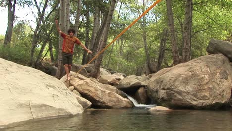 Mediumshot-Of-A-Young-Man-Slacklining-Across-A-Swimming-Hole
