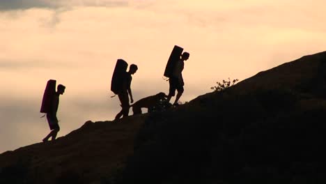 Mediumshot-Of-A-Group-Of-Silhouetted-Backpackers-And-A-Dog-Climbing-A-Rock-Structure