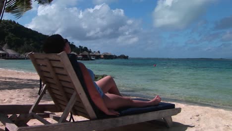 A-woman-relaxes-on-a-beach-chair-on-a-tropical-island-paradise