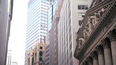 Low-angle-pan-right-view-of-skyscrapers-lining-Wall-Street-in-New-York-City