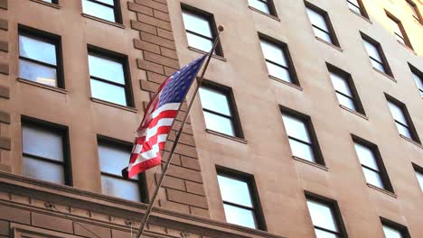 The-American-flag-waves-from-a-building-on-Wall-Street-in-New-York-City