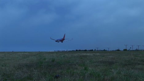 A-jet-airplane-lands-on-an-airport-runway-against-darkened-skies