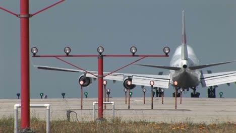 A-747-jet-lands-on-an-airport-runway-behind-lights-and-guide-beacons