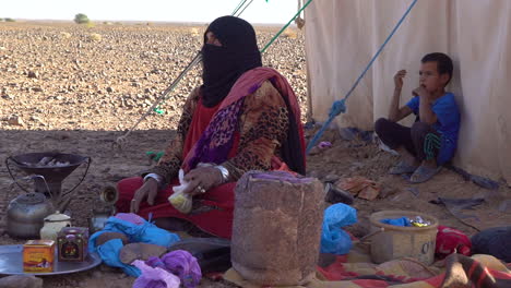 A-Muslim-woman-and-her-children-sit-outside-their-tent-in-the-desert-of-Morocco