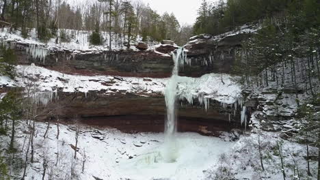 Schöne-Winterluftaufnahme,-Die-Zu-Einem-Wasserfall-In-Einer-Gefrorenen-Landschaft-Fliegt
