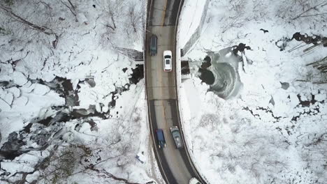 An-aerial-POV-perspective-looking-straight-down-on-a-car-traveling-on-a-highway-through-a-frozen-wilderness