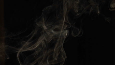 Closeup-of-incense-smoke-rising-against-a-black-background