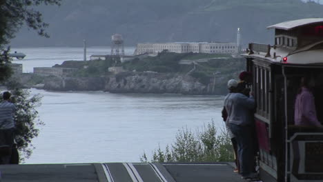 Passengers-get-off-a-trolley-car-on-a-street-overlooking-Alcatraz
