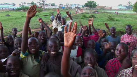 Medium-shot-of-a-crowd-of-niños-at-a-refugee-camp-Uganda-Africa-waving-at-the-camera