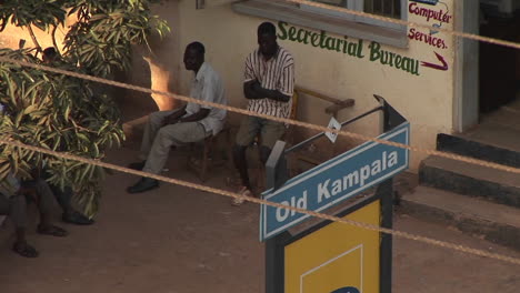 Los-Hombres-Se-Sientan-Fuera-De-La-Oficina-De-Secretaría-En-Kampala,-Uganda
