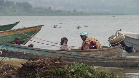 Mediumshot-De-Pescadores-Africanos-Descansando-En-Un-Barco-En-La-Orilla-Del-Lago-Victoria,-Uganda