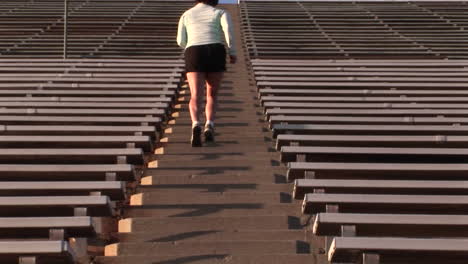 Crab-left-of-a-woman-run-up-the-steps-of-a-large-stadium