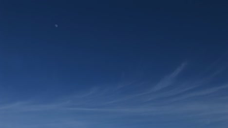 Wormseye-view-of-a-blue-sky-with-wispy-clouds-and-a-distant-moon
